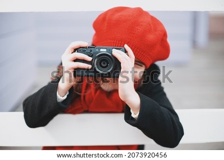 a young girl in a red beret and scarf takes pictures on the city street. High quality photo