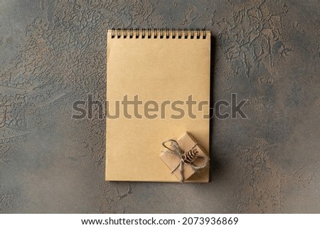 Christmas or New Year holiday background with an open notebook and gift box. The concept of a checklist of gifts or a letter to Santa. Top view with a copyspace