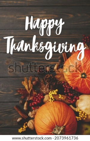 Happy Thanksgiving Card. Happy thanksgiving text on pumpkins, autumn leaves, anise, berries, acorns border on rustic wood flat lay. Season's greetings, handwritten lettering. Give thanks