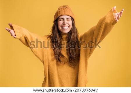 Hurray. Portrait of delighted girl yelling for happiness, enjoying life, rejoicing success with arms raised, celebrating triumph, stretching to somebody. Studio shot isolated on yellow background  Royalty-Free Stock Photo #2073976949