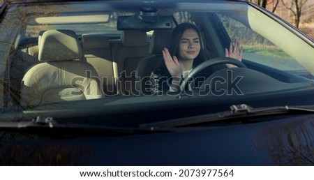 Angry young woman sitting in car and pounding with hands on steering wheel after traffic violation accident while while waiting car assistance.
