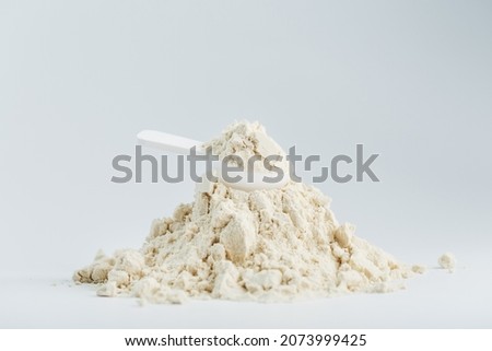 A mountain of soy protein isolate in powder with a measuring spoon on a white background. Vegetarian sports nutrition for cocktails Royalty-Free Stock Photo #2073999425
