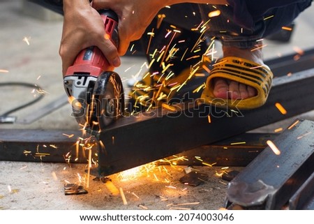 without safety gloves at work. Construction workers do not wear gloves and safety shoes to work. Workplace is not safe. Close up hand worker electric saw wheel grinding cutting
 a steel in factory.  Royalty-Free Stock Photo #2074003046