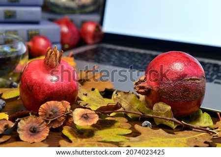 Autumn still life with laptop, books and pomegranates