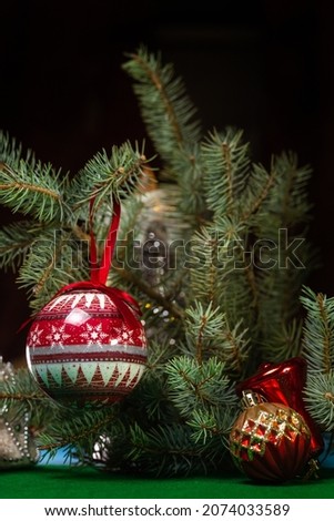 red decorative Christmas ball on a branch of a green fir tree.