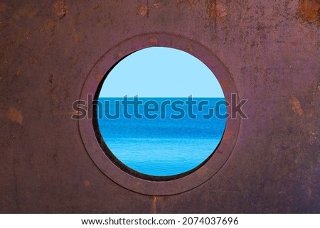 Porthole with ocean view. View of the silent sea surface through a rusty porthole of the ship. Old ship cabin window Royalty-Free Stock Photo #2074037696
