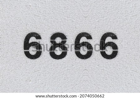 Black Number 6866 on the white wall. Spray paint. Number six thousand eight hundred and sixty six.