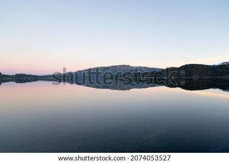 Enchanting view of the placid lake at sunset. The mountains, forest and blue sky reflection in the water. Royalty-Free Stock Photo #2074053527