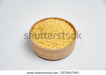 millet grains in a wooden bowl on a white background, subject photography