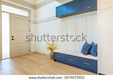 Foyer front entry with white door white walls denim blue seat with white cabinets Royalty-Free Stock Photo #2074073903