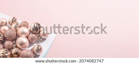 Beautiful shiny pink decorative balls on a pink background. Top view, flat lay. Banner
