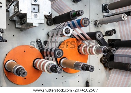 Rotary die cutting machine with slitting blade system. Production of duct tape.Packing tape manufacturing. Modern machine for packaging line in factory, Industrial and technology concept. Royalty-Free Stock Photo #2074102589