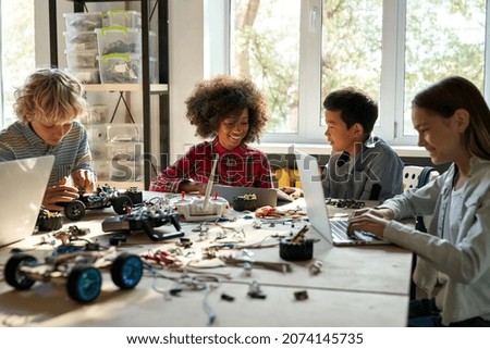 Group of multiethnic schoolkids interacting using gadgets for programming for robotics engineering class. Elementary school science classroom of futuristic technologies. STEM education concept. Royalty-Free Stock Photo #2074145735