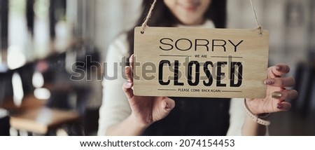 Small business owner turning closed sign board on the entrance door. 