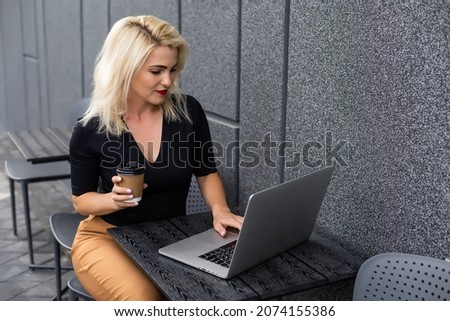 Image of young beautiful joyful woman smiling while working with laptop from outside
