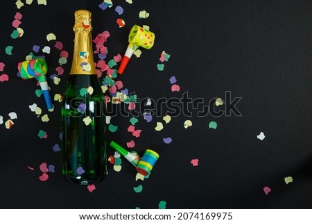 New Year's Eve and New Year's Eve celebrations. Black background. Copy space. Noise maker and bottle of champagne.