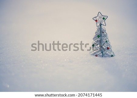 The Christmas background with small decorative Christmas tree in the white, fluffy snow. Greeting card image with space for copy.