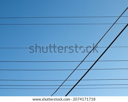 A photo of street lighting wires with a clear sky in the background.
