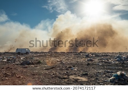 Landfill with burning trash piles. Environment pollution concept. Birds flying over the trash dump Royalty-Free Stock Photo #2074172117