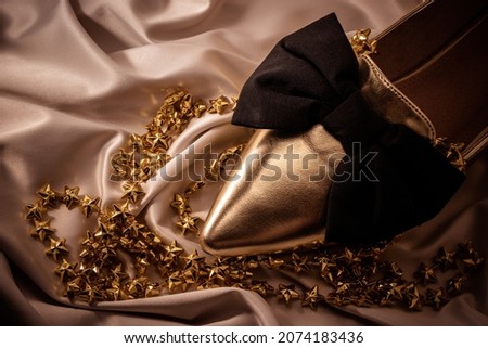 Christmas composition with golden ballerinas shoe and gold shiny stars on ivory white silk fabric at night time. Festive party concept. New year or Christmas card