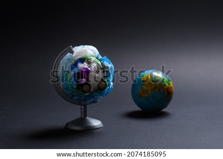 Planet garbage pollution concept. Globe made of debris on the background of the lying planet on a dark background. Selective focus on a debris globe