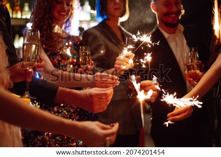 Sparkling sparklers in the hands. Playing firework to celebrate winter holidays with friends at the party. Magic New Year, Christmas.