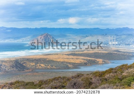 Morro bay. View from Montana de Oro State Park. Cliffs, sandy beach, Morro Rock, mountains and cloudy sky on background, California Central Coast