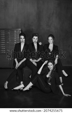 Stylish young girls in pantsuits pose in a photo studio.