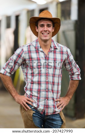 portrait of american cowboy standing in stables Royalty-Free Stock Photo #207427990
