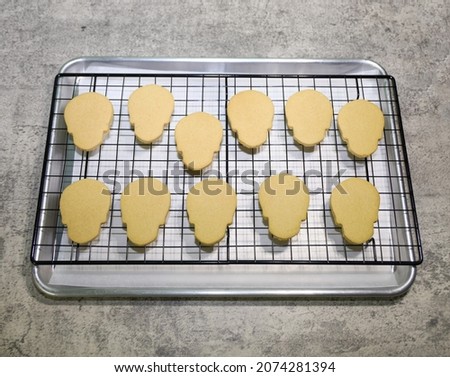 Day of the dead (dia de muertos) skull shaped sugar cookies on a cooling rack to decorate with royal icing. 