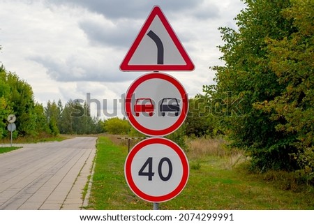 road sign that limits the speed to 40 km where the winding road is marked with a yellow zigzag sign. There is no overtaking sign.