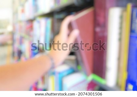 Blurred of student's hand pick a hard cover book from bookshelf in library. Education and book's day concept.