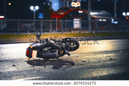 Motorcycle lying on asphalt after an road accident. Moto bike collision at night. Damaged motorcycle lay on asphalt road Royalty-Free Stock Photo #2074316275