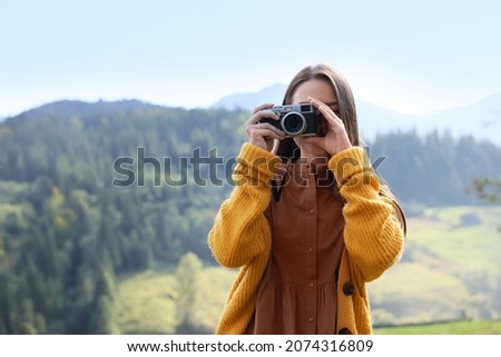 Woman taking photo with camera in mountains