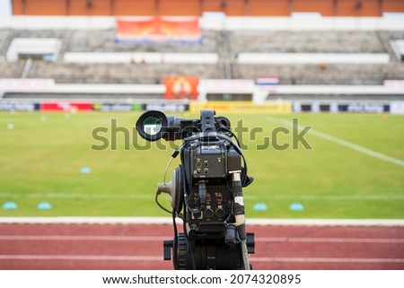 Video camera before live video streaming at the soccer green glass field background.Camera for cameraman recording football tournament at media press corner. Live streaming concept. Royalty-Free Stock Photo #2074320895