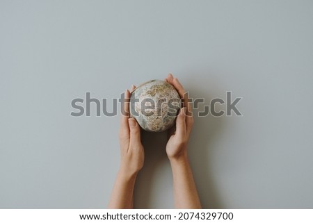 Woman hands hold small globe on blue background. World, planet Earth model in hands. Save the Earth and environment concept. Flat lay, top view