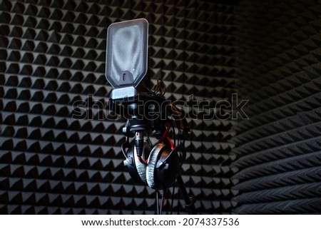 Professional studio condenser microphone in recording studio with studio headphones on a sound acoustical foam Background in record room