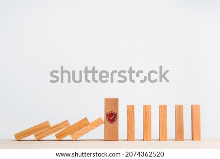 The big wooden block strong with shield security icon symbol standing protects falling domino pieces isolated on white. Stopping the domino effect. Business data management. Risk protection.