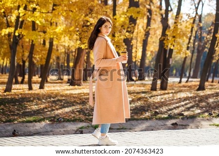 Full length portrait of a young beautiful girl posing against the backdrop of an autumn park