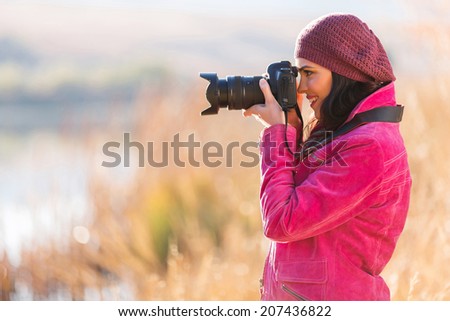 happy female photographer taking photos outdoors in fall