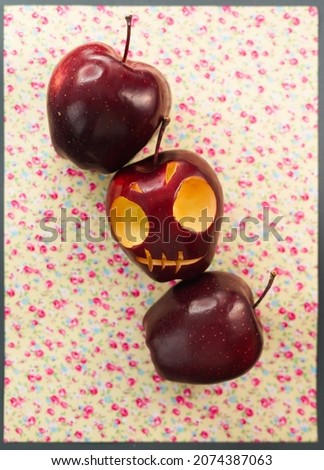 Three apples, one is a skull, cut from a red apple on a cute floral background