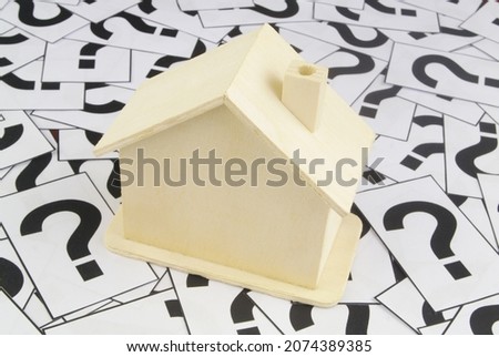 Real estate question and consultation concept. Wooden house model on question marks background.