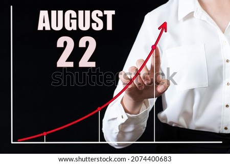 22nd day of august. Businesswoman's hand pointing to the graph and a calendar with the date of 22 august. Business goals for the day. Summer month, day of the year concept.
