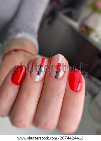  Women's red manicure with design.Hands of a woman with red manicure on nails. Manicure beauty salon concept.Red nail art