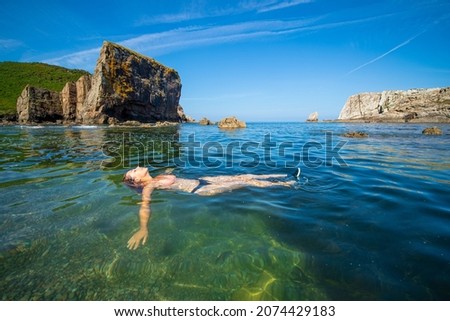 Full body portrait of a relaxed tourist woman floating on the ocean of a paradise beach
