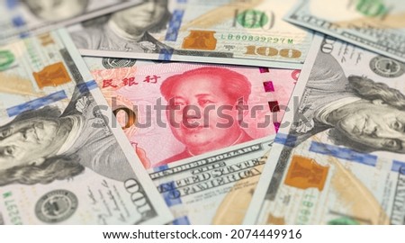 100 yuan banknote among 100 US dollar banknotes  Royalty-Free Stock Photo #2074449916