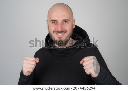 Brutal man in black hoodie isolated smiling looking at camera
