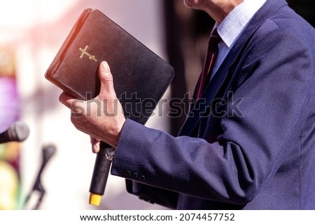 Pastor with a Bible in his hand during a sermon. The preacher delivers a speech Royalty-Free Stock Photo #2074457752