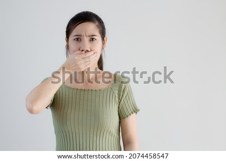 Asian beautiful woman wear green t-shirt use hand cover mount conceal secret and keep silence or unconfidence and worry with bad breath. Or feeling shock when get bad news. Royalty-Free Stock Photo #2074458547