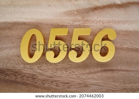 Golden Arabic numerals 0556 on a dark brown to white wood grain background.